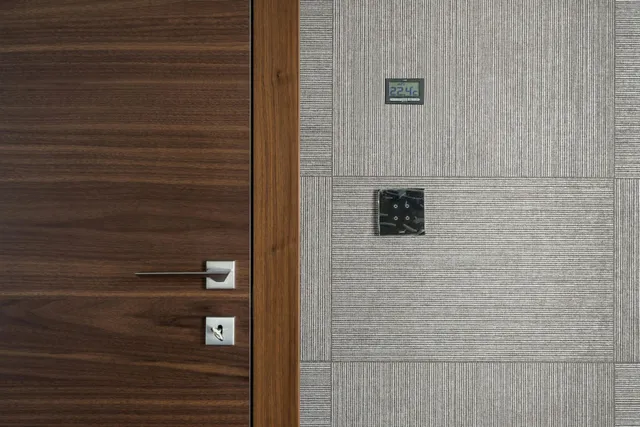 A close up of a wooden door next to a tiled wall