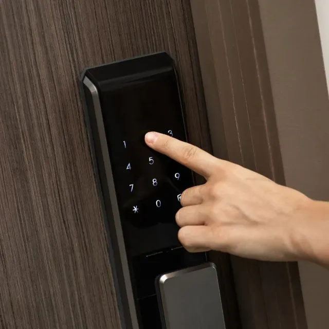 Person entering a PIN on a touchscreen smart lock installed on a home door in Montgomery